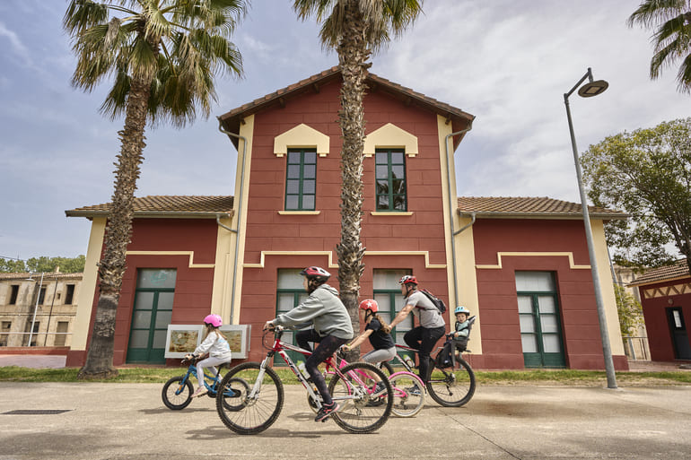 Família pedalant davant de l'estació d'Anglès
