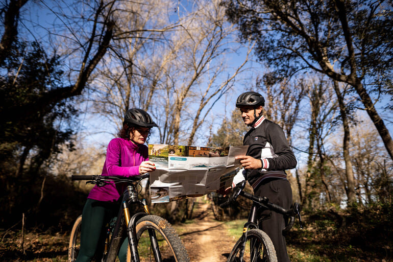 Ciclistes consultant un mapa de les Ecovies de Girona a la via verda del Pla Gironès Sud