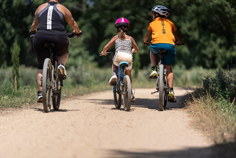 Família amb bicicletes pedalant a la via verda del Tren Petit