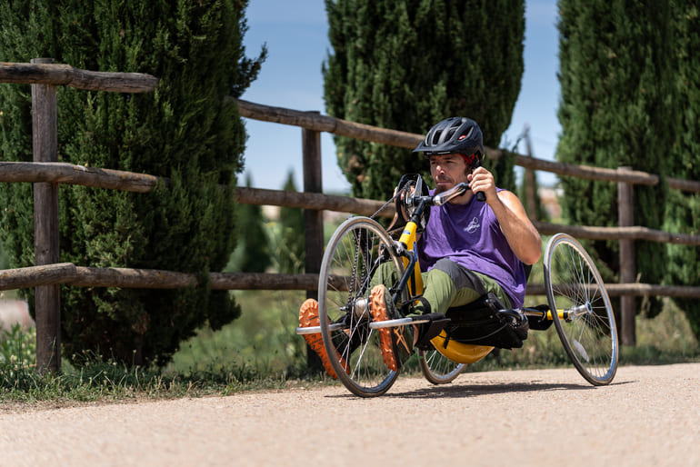 Jove circulant amb una handbike a la via verda del Tren Petit